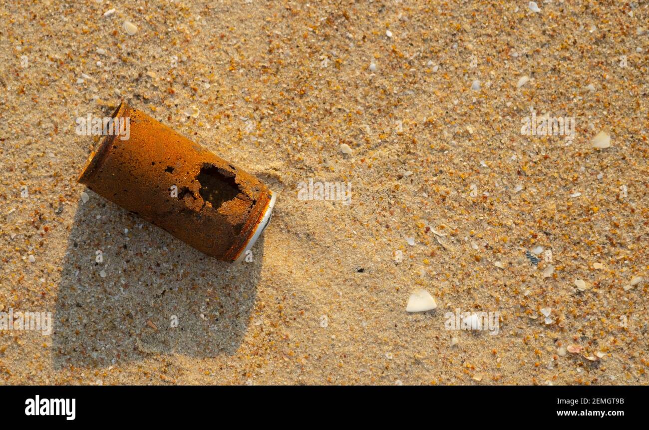 Old rusty can dropped on the sand beach, environmental problems and global warming, top view photo. Stock Photo
