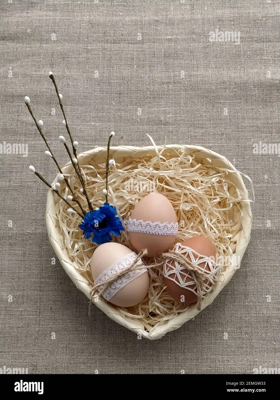 Easter composition decorated by lace Easter eggs in wicker basket on linen background Stock Photo