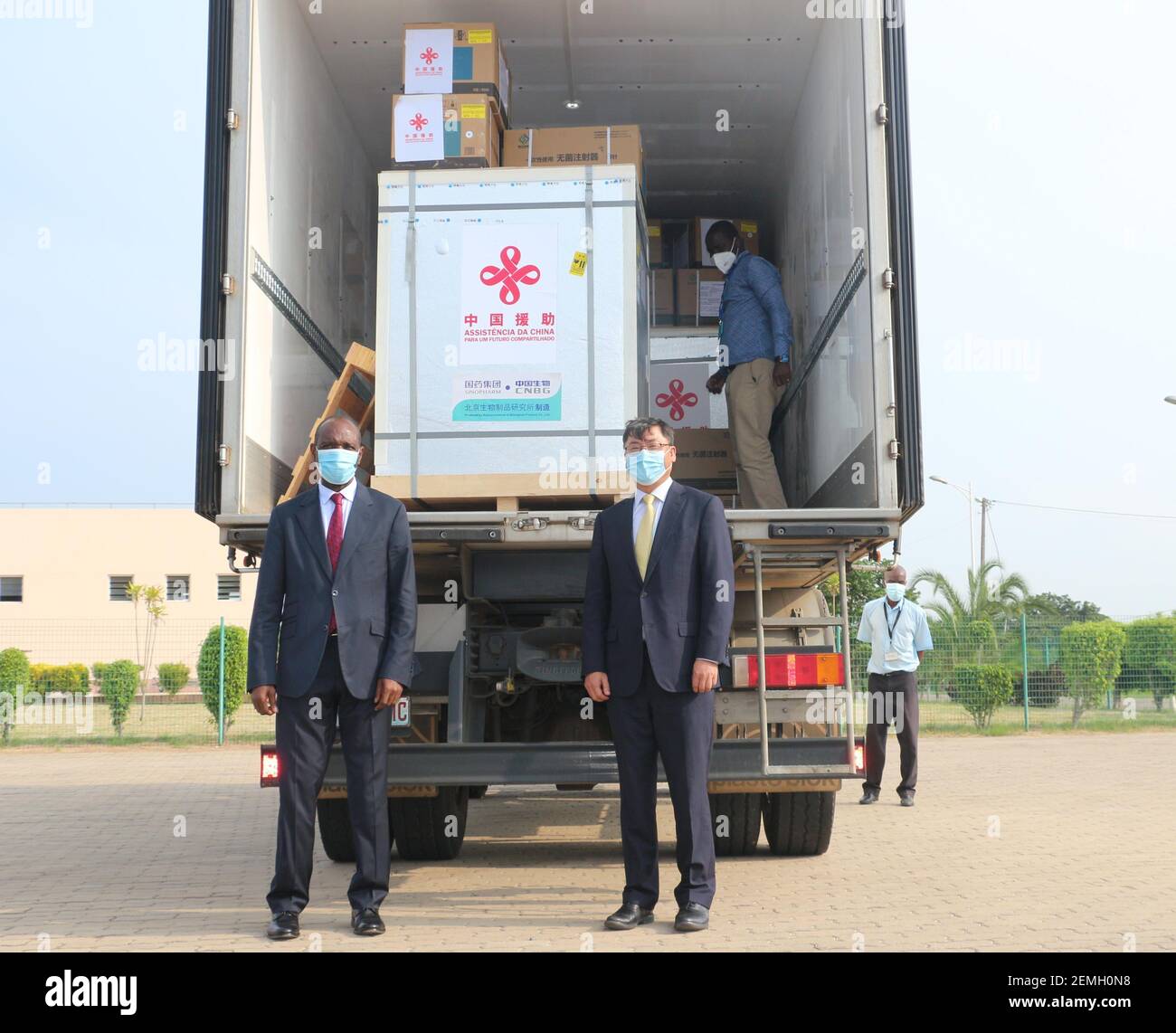 (210225) -- MAPUTO, Feb. 25, 2021 (Xinhua) -- Mozambican Prime Minister Carlos Agostinho do Rosario (L, front) and Chinese Ambassador to Mozambique Wang Hejun (R, front) stand in front of the COVID-19 vaccines donated by China at the Maputo International Airport in Maputo, Mozambique, Feb. 24, 2021. A batch of COVID-19 vaccines donated by China arrived here on Wednesday to help the African country fight against the COVID-19 pandemic, and it was also the first batch of COVID-19 vaccines received by the country. (Photo by Ge Peiyao/Xinhua) Stock Photo