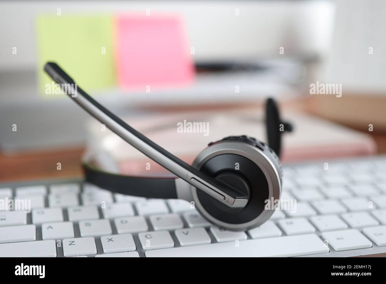 Black headset lying on computer keyboard closeup Stock Photo