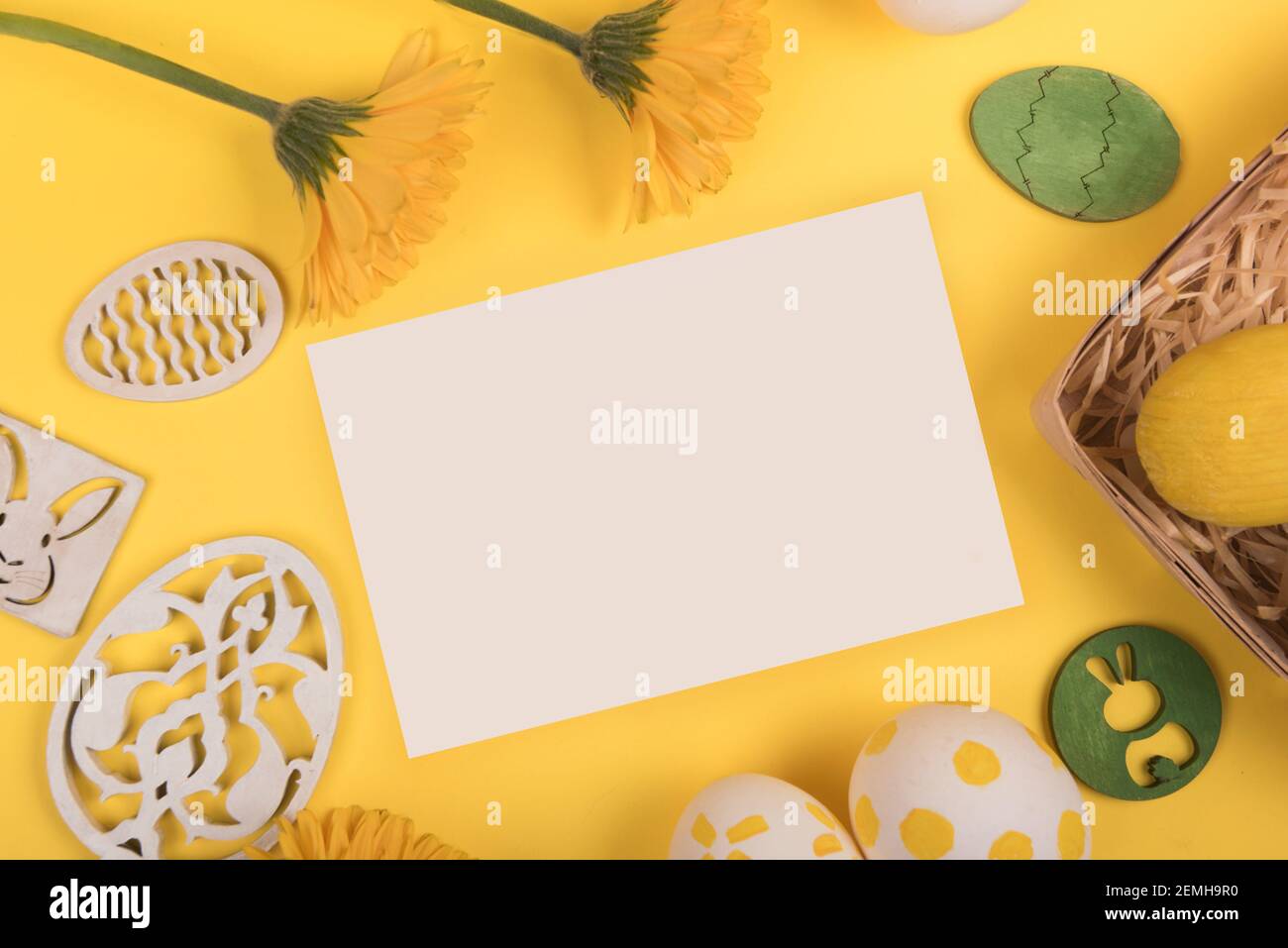 Flat lay with painted easter eggs, gerbera flower and easter decorations on yellow background. copy space Stock Photo