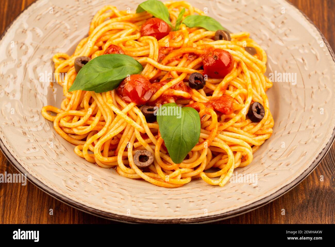 Pasta spaghetti Napoli or Napolitana on plate on brown wooden background. Italian cuisine. Stock Photo