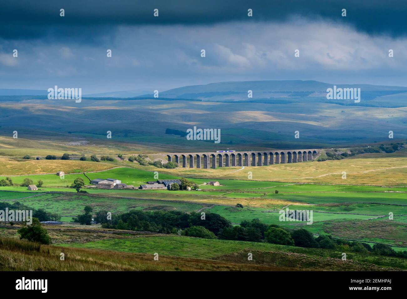 Scenic countryside view (Northern locomotive crossing Ribblehead Viaduct, hilly uplands, valley & hills, dramatic sky) - Yorkshire Dales, England UK. Stock Photo