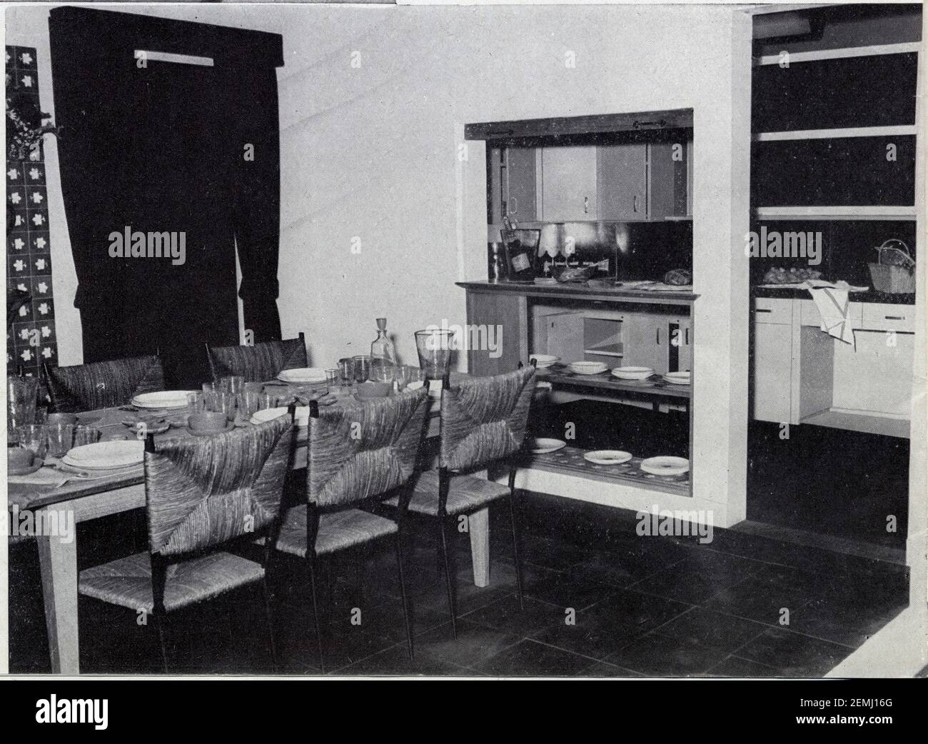 Table en chêne, chaises en fer forgé, paille verte, sol ardoises, cuisine  avec mobilier Cepac. Création de Colette Gueden Stock Photo - Alamy