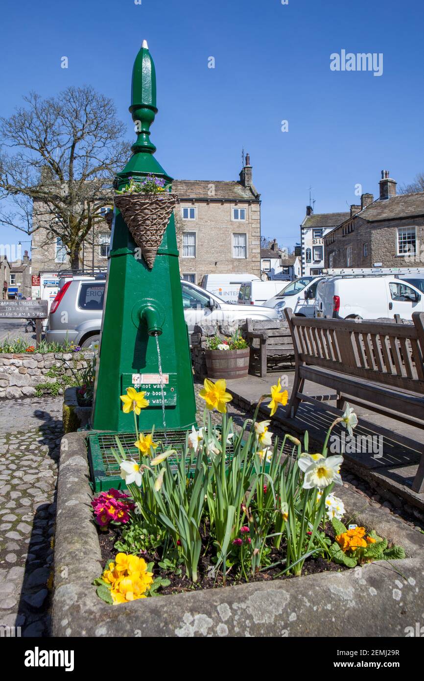 Spring view of the painted old water pump and trough, filled with flowers in Grassington, North Yorkshire Stock Photo