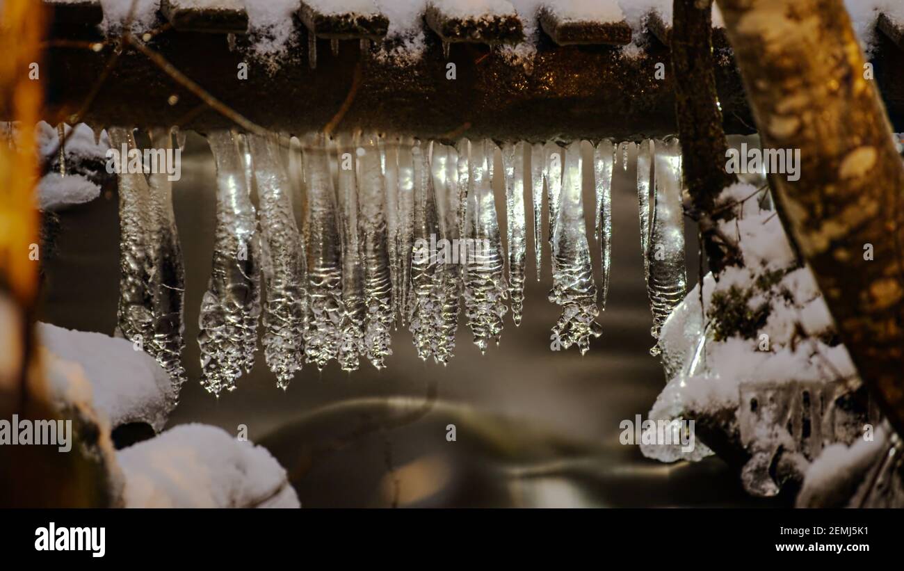 Row of pine cone shaped icicles hanging from a small bridge. Stock Photo