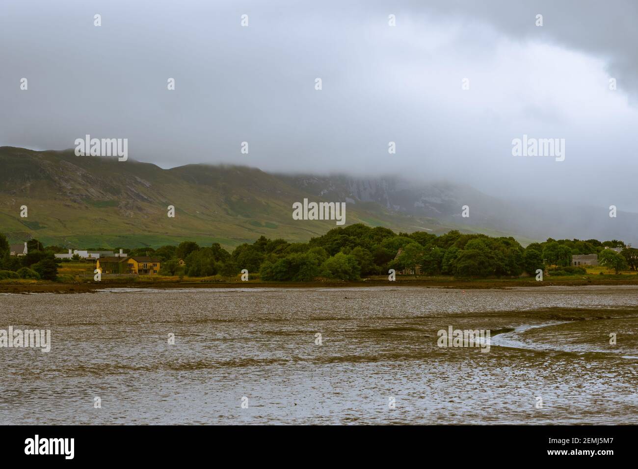 Fog rolls down a mountain toward a dry  river bank in County Mayo, in Westport Ireland. Stock Photo