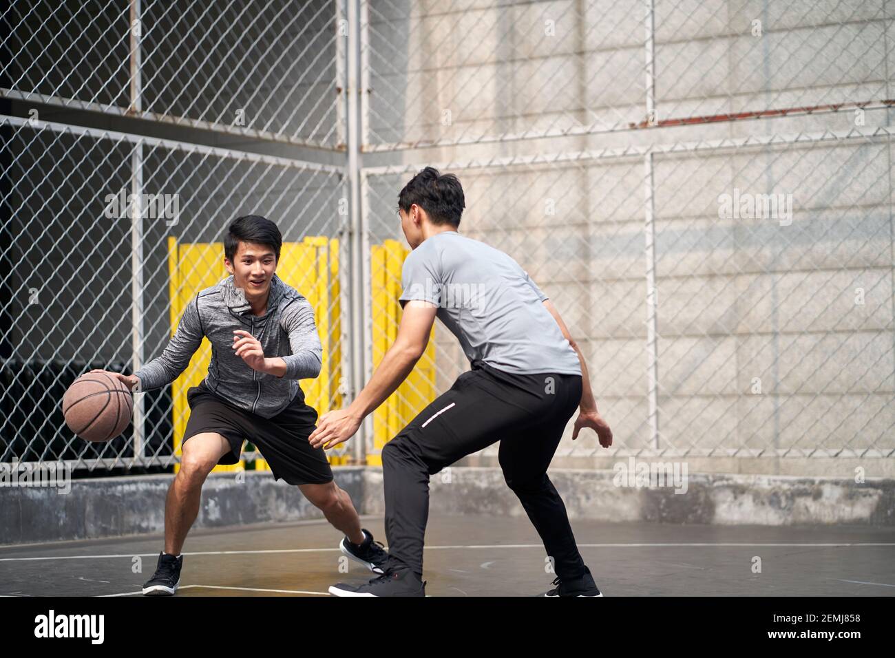two young asian adult men playing one-on-one basketball on outdoor court Stock Photo
