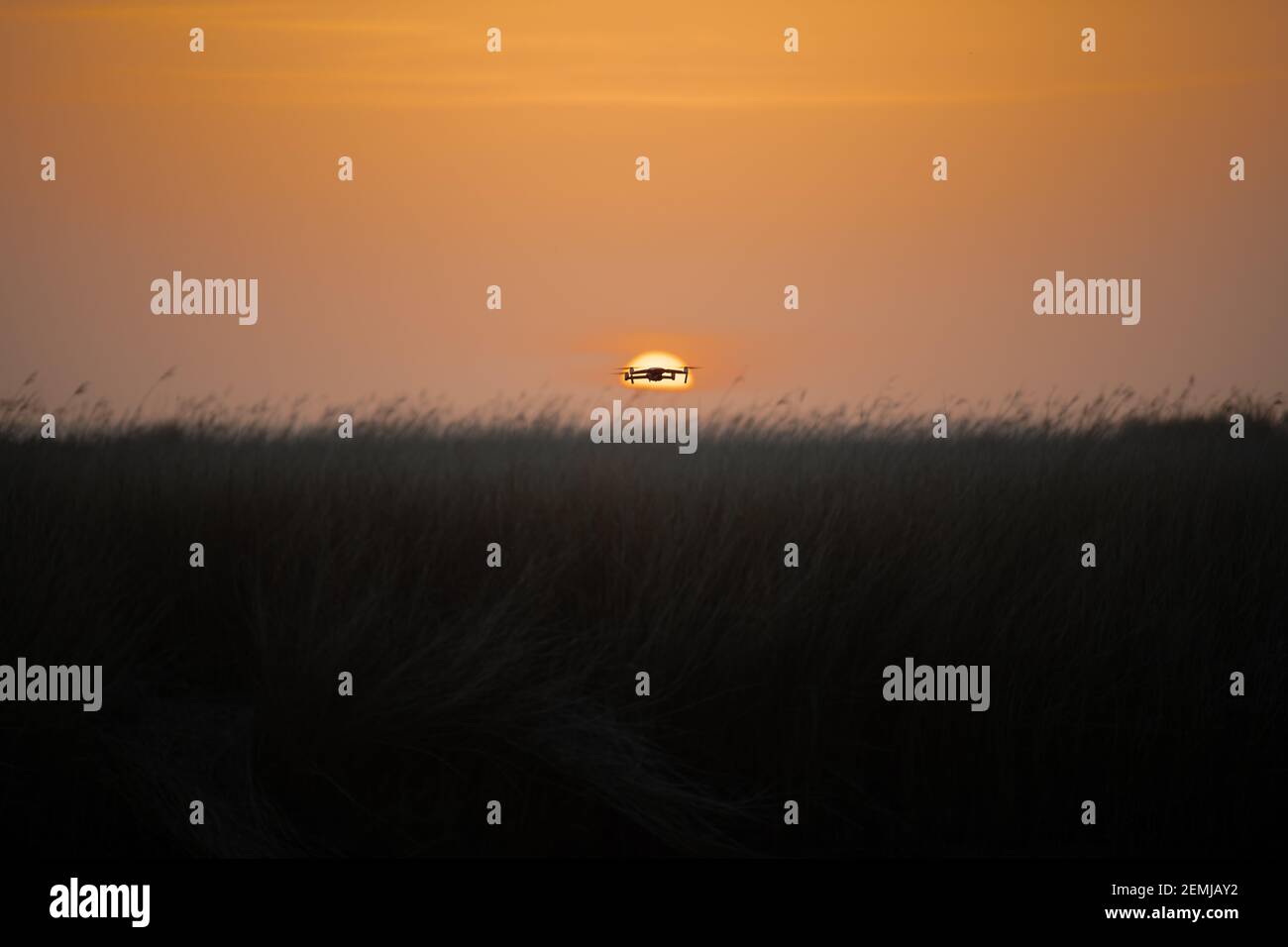 Drone quadcopter with digital camera in flight at sunset, Silhouette of drone at sunset Stock Photo