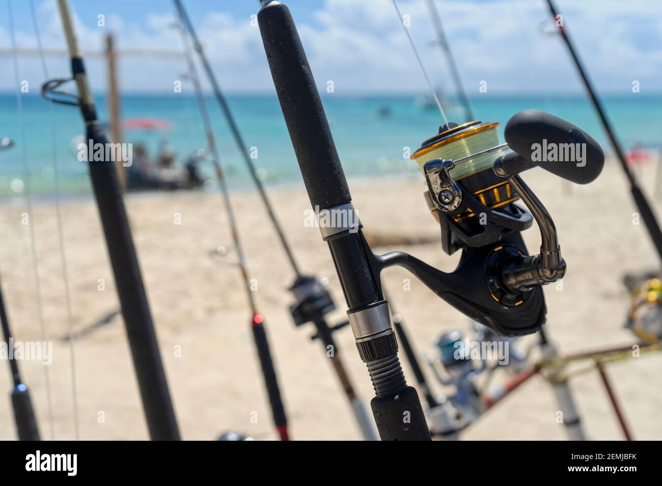 Foreground fishing rod and reel facing the sea, in the background the  Caribbean Ocean and boats moored in a Mexican beach Stock Photo - Alamy