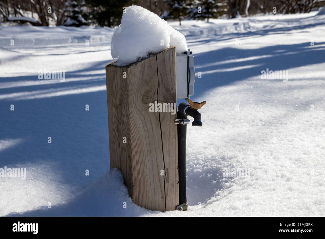 A water and electric hookup covered by snow during winter season on a closed campsite, water pump foutain Stock Photo