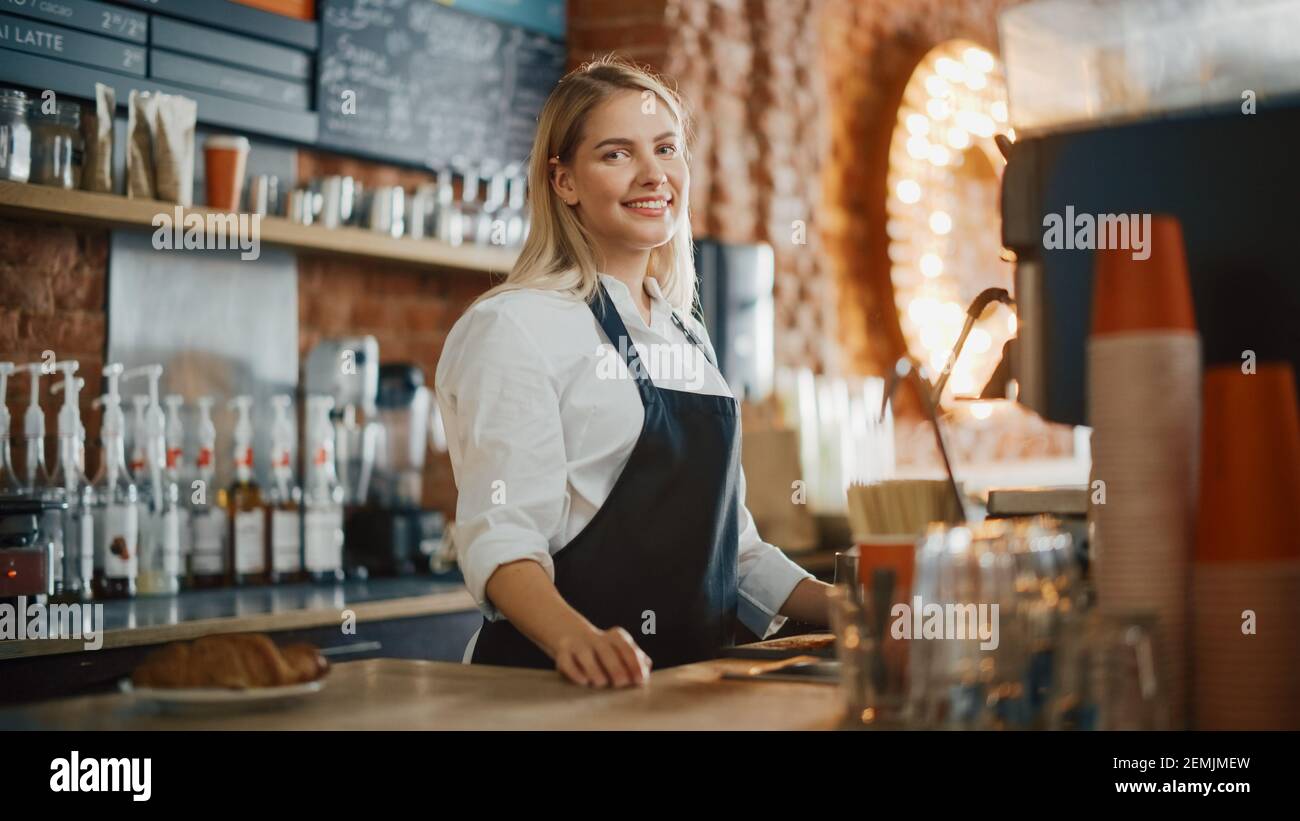 Beautiful Young Caucasian Barista with Blond Hair is Making a Cup of Fresh Coffee in a Cafe. Happy and Smiling Bar Employee Posing while Working in a Stock Photo