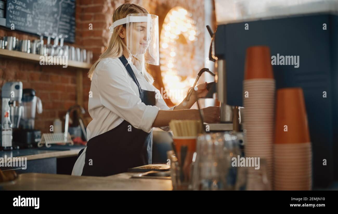 Beautiful Young Barista Wearing Face Shield is Making a Cup of Fresh Coffee in a Cafe. Bar Employee Working in Coffee Shop Restaurant. Social Stock Photo