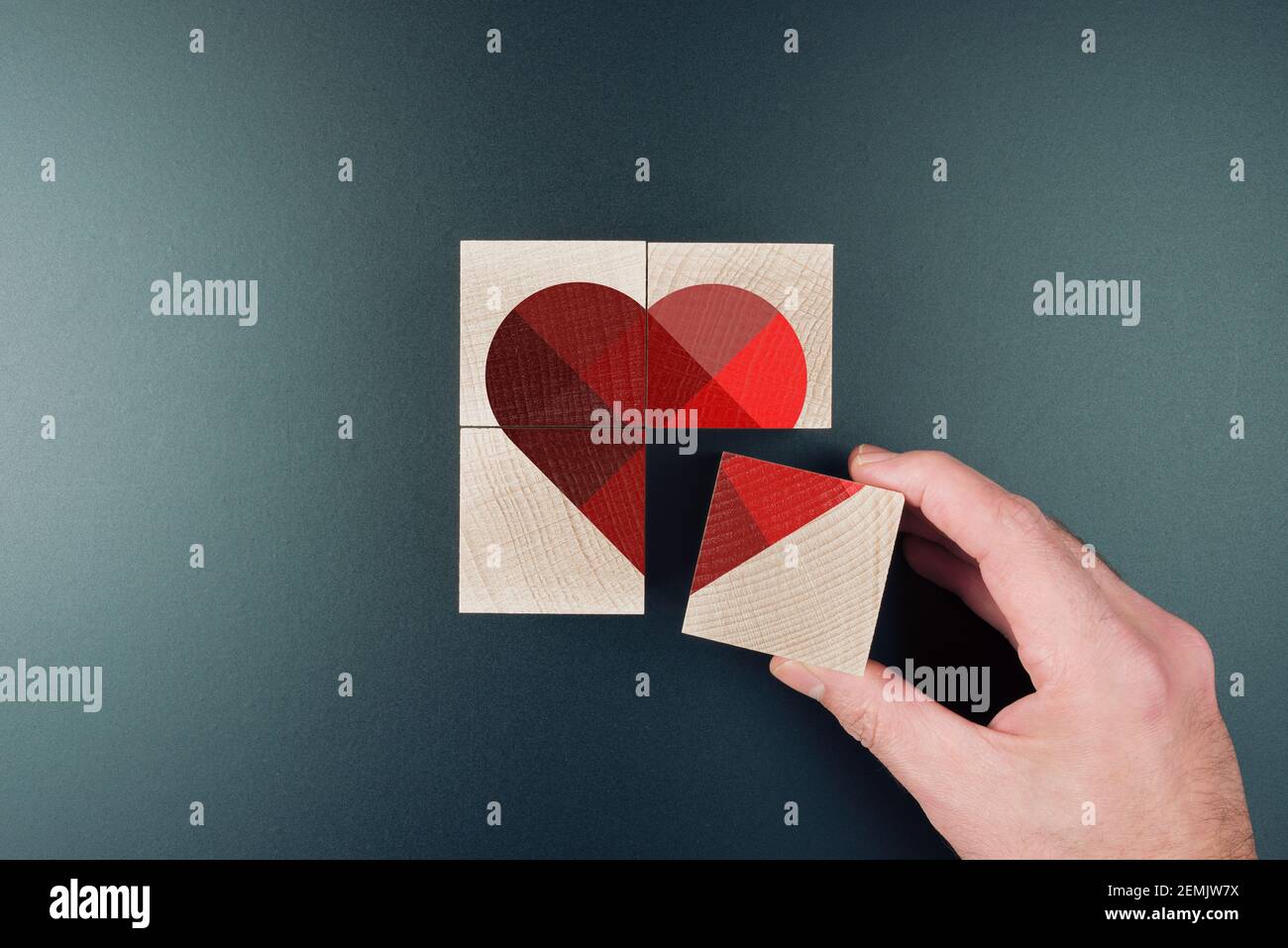 above view of person piecing together heart shape on wooden blocks, love and romance concept Stock Photo