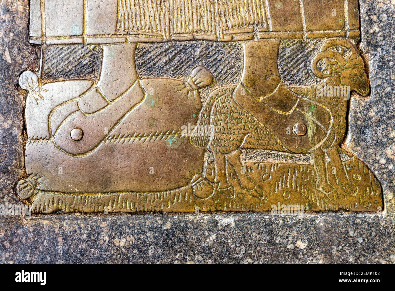 A detail of the memorial brass of the wool merchant Thomas Bushe (c. 1525) showing his feet on a woolsack and a sheep in Northleach church UK. Stock Photo