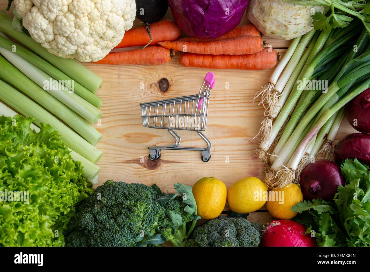 Various vegetables and tiny market car on wood. Buying healthy vegetables from the market. Stock Photo