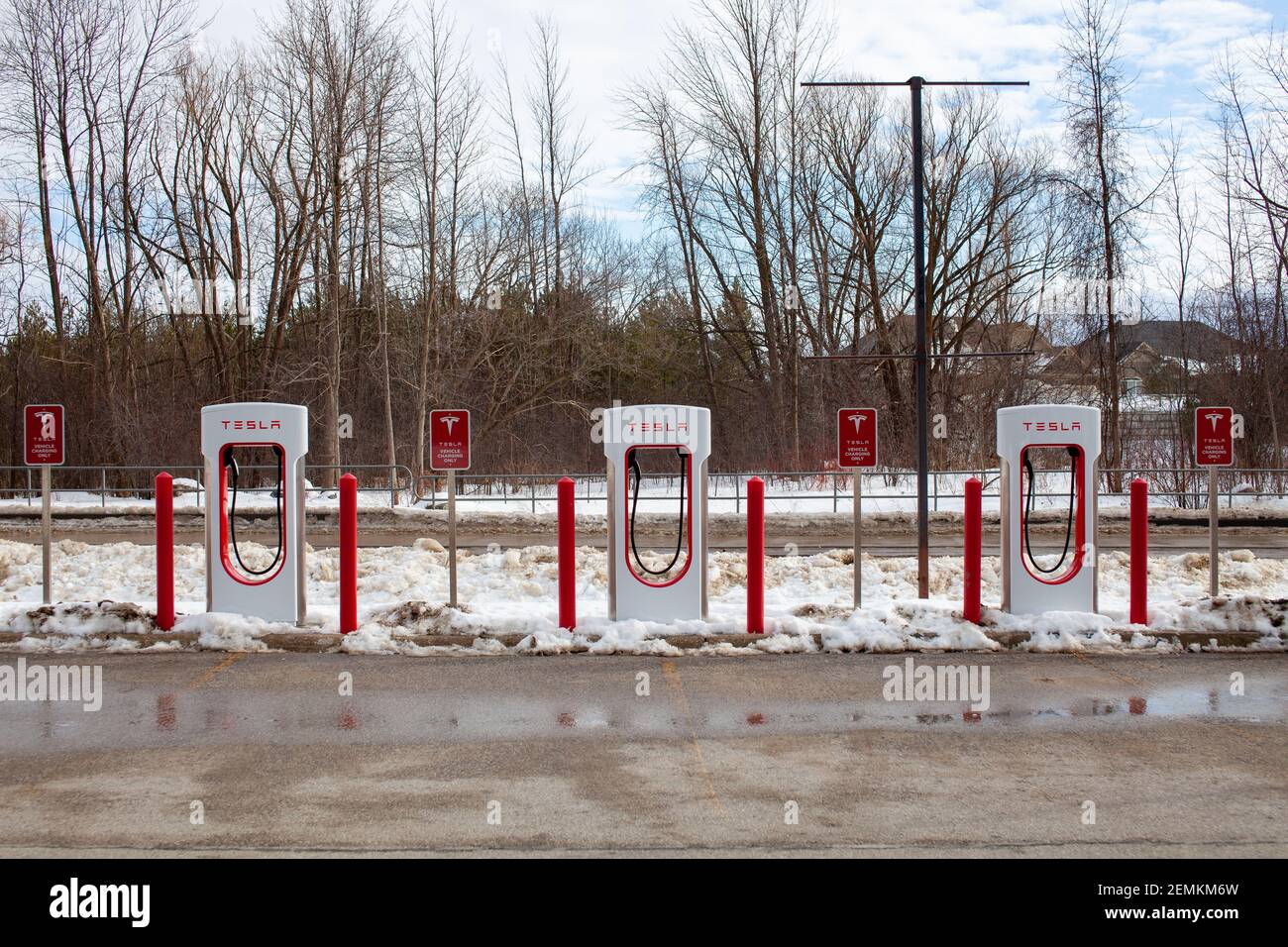 Collingwood, Ontario, Canada - 02-23-2021: Brand new Tesla EV electric car charging Supercharger stations line the parking lot at the Cranberry Mews s Stock Photo