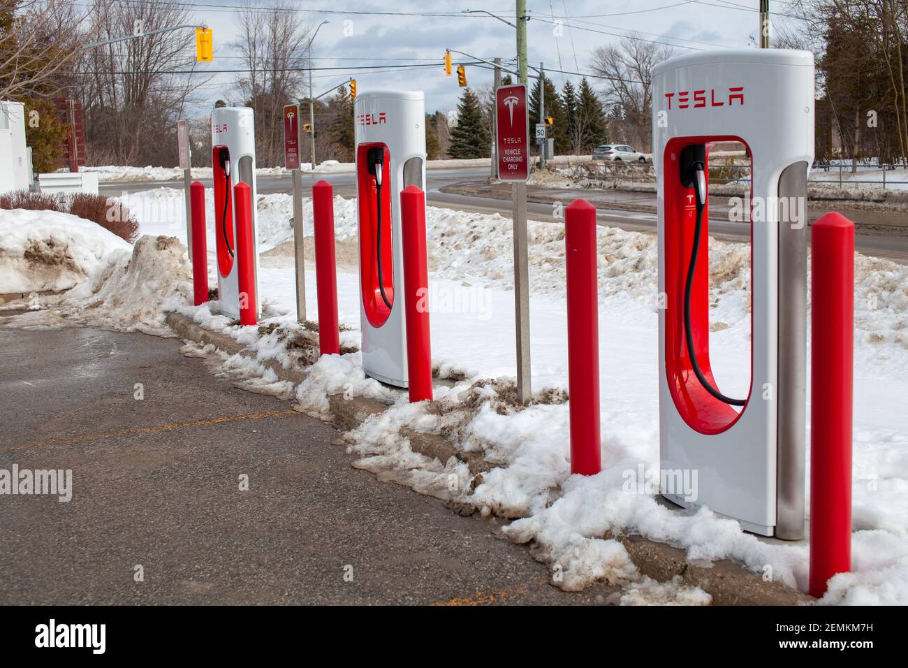 Collingwood, Ontario, Canada - 02-23-2021: Brand new Tesla EV electric car charging Supercharger stations line the parking lot at the Cranberry Mews s Stock Photo