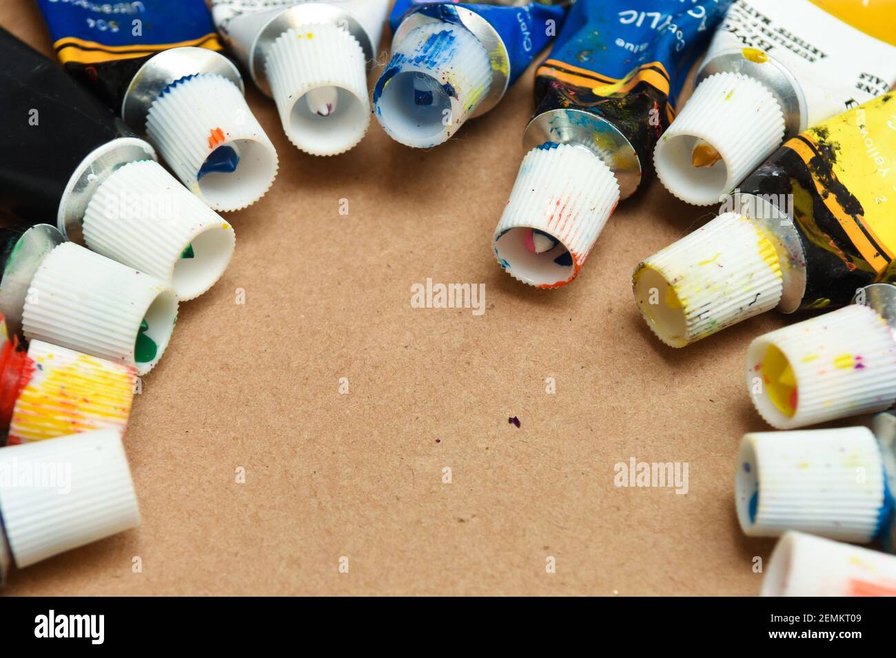 Tubes of art paint with variety of colours on paper background Stock