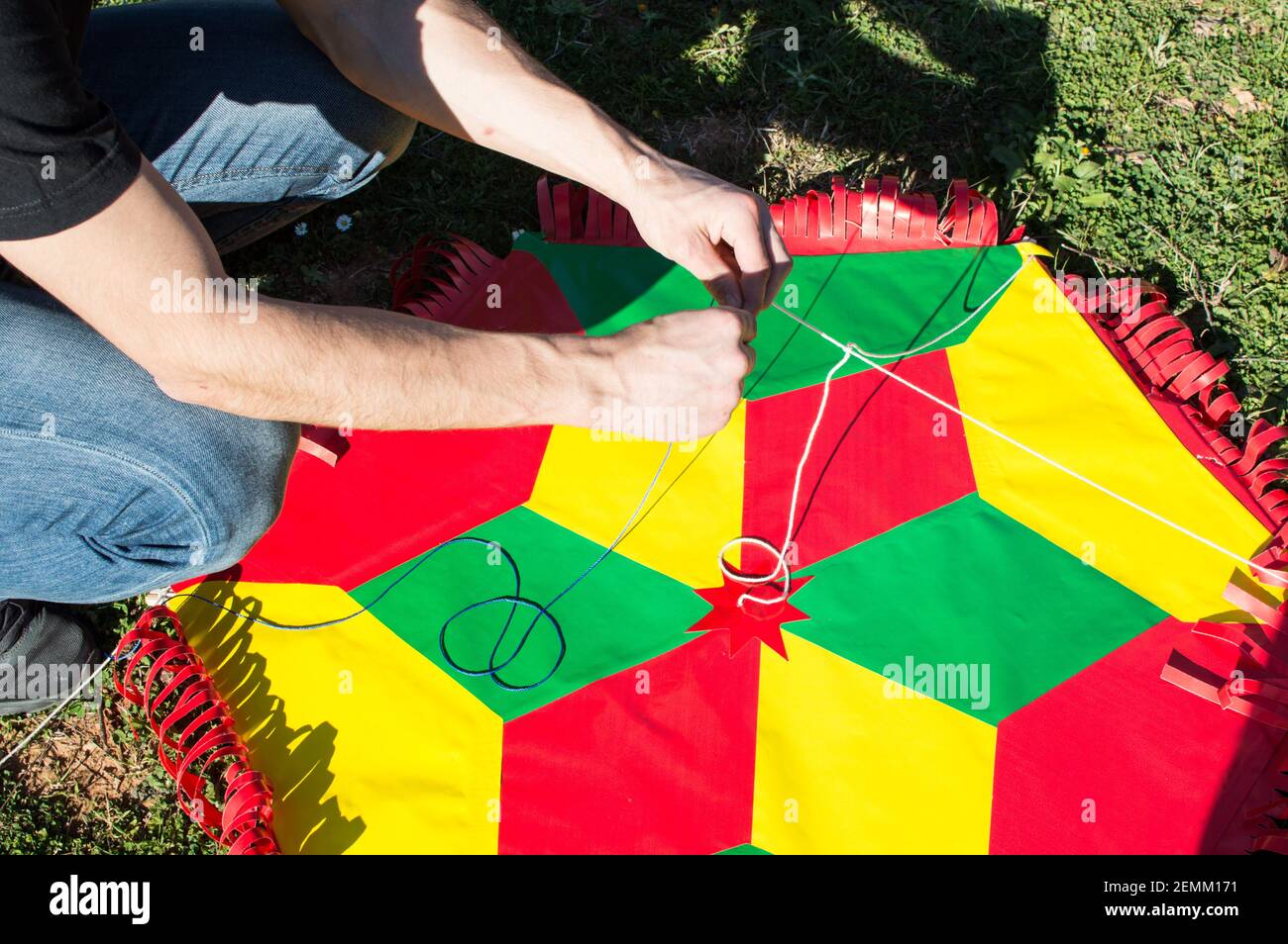 A man seen fixing the strings of a kite. In Clean Monday people are