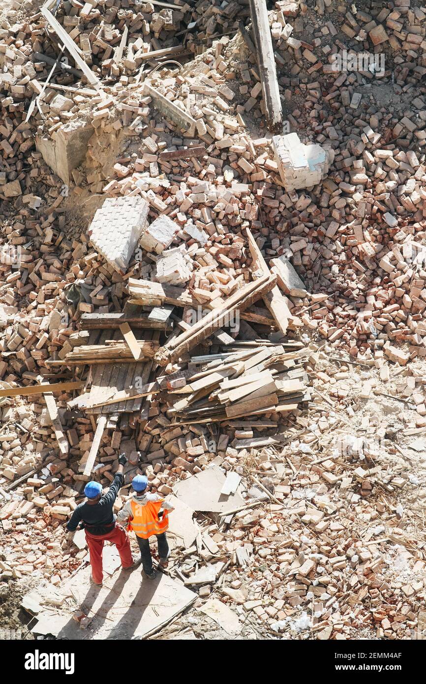 Two unidentified men inspect building demolition or explosion site, view from above. Stock Photo