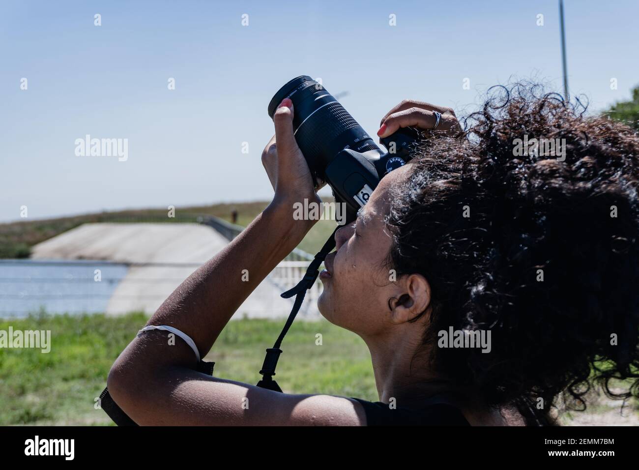 afro american woman with a professional camera taking pictures of the sky at the north waterfront. vicente lopez. buenos aires. Stock Photo
