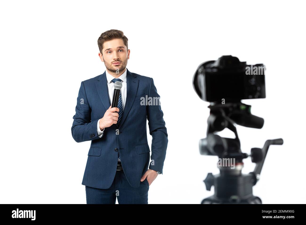 young broadcaster holding microphone near digital camera on blurred ...