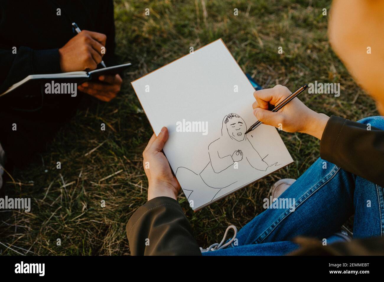 Cropped image of man's hands sketching in book at park Stock Photo