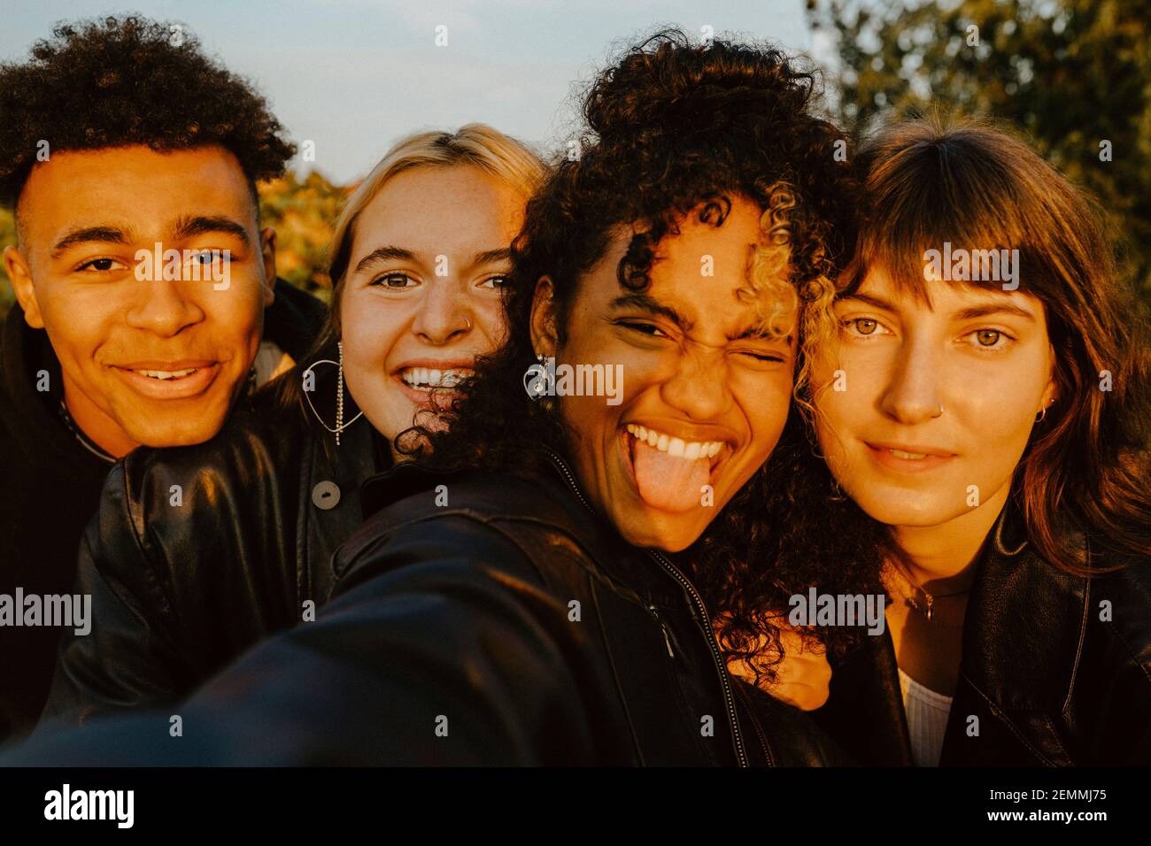 Cheerful friends taking selfie outdoors during sunset Stock Photo