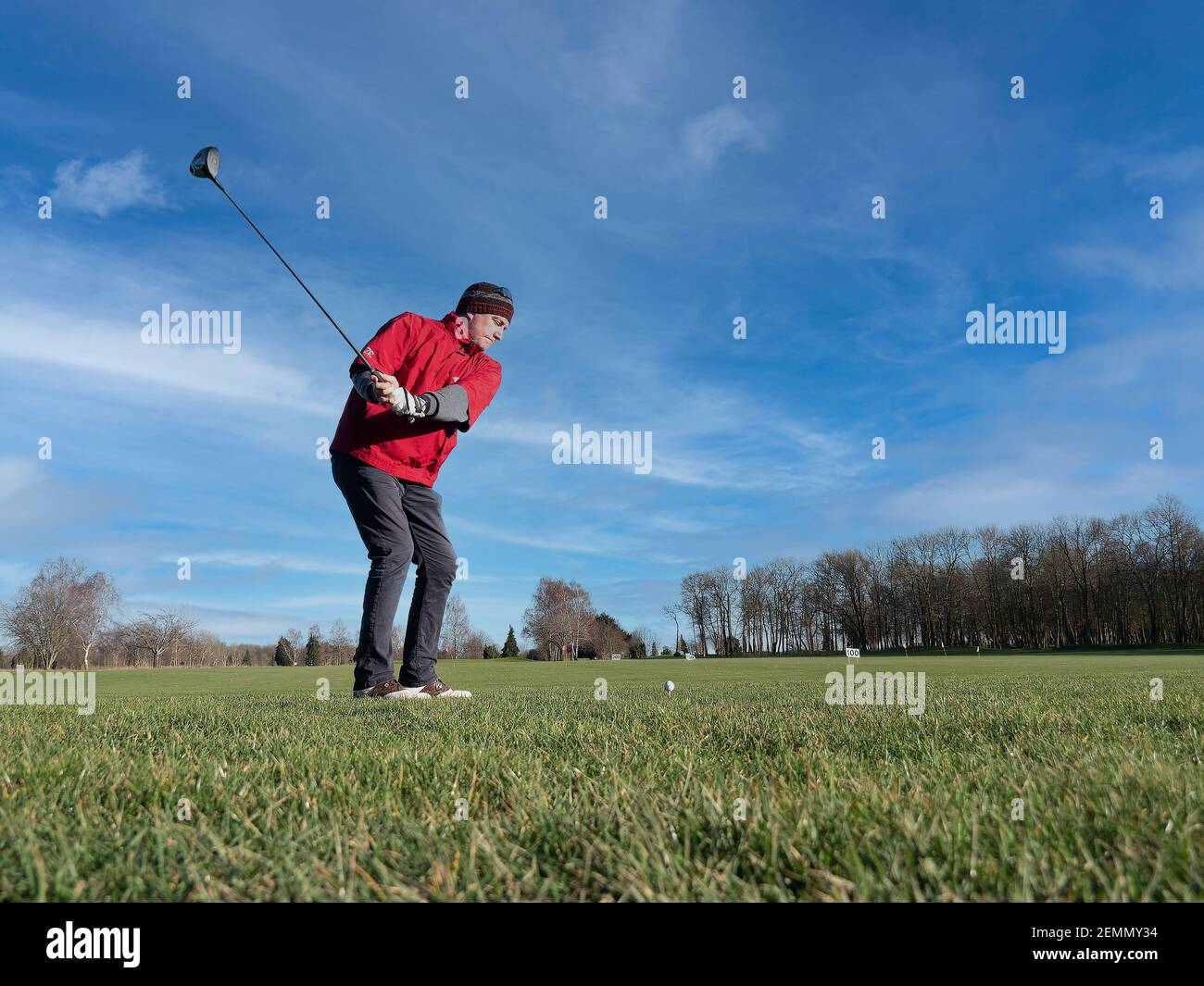 Caen, France, February 2021. A golf course and a player practicing long hitting backwards, from below you can see green grass, blue sky Stock Photo