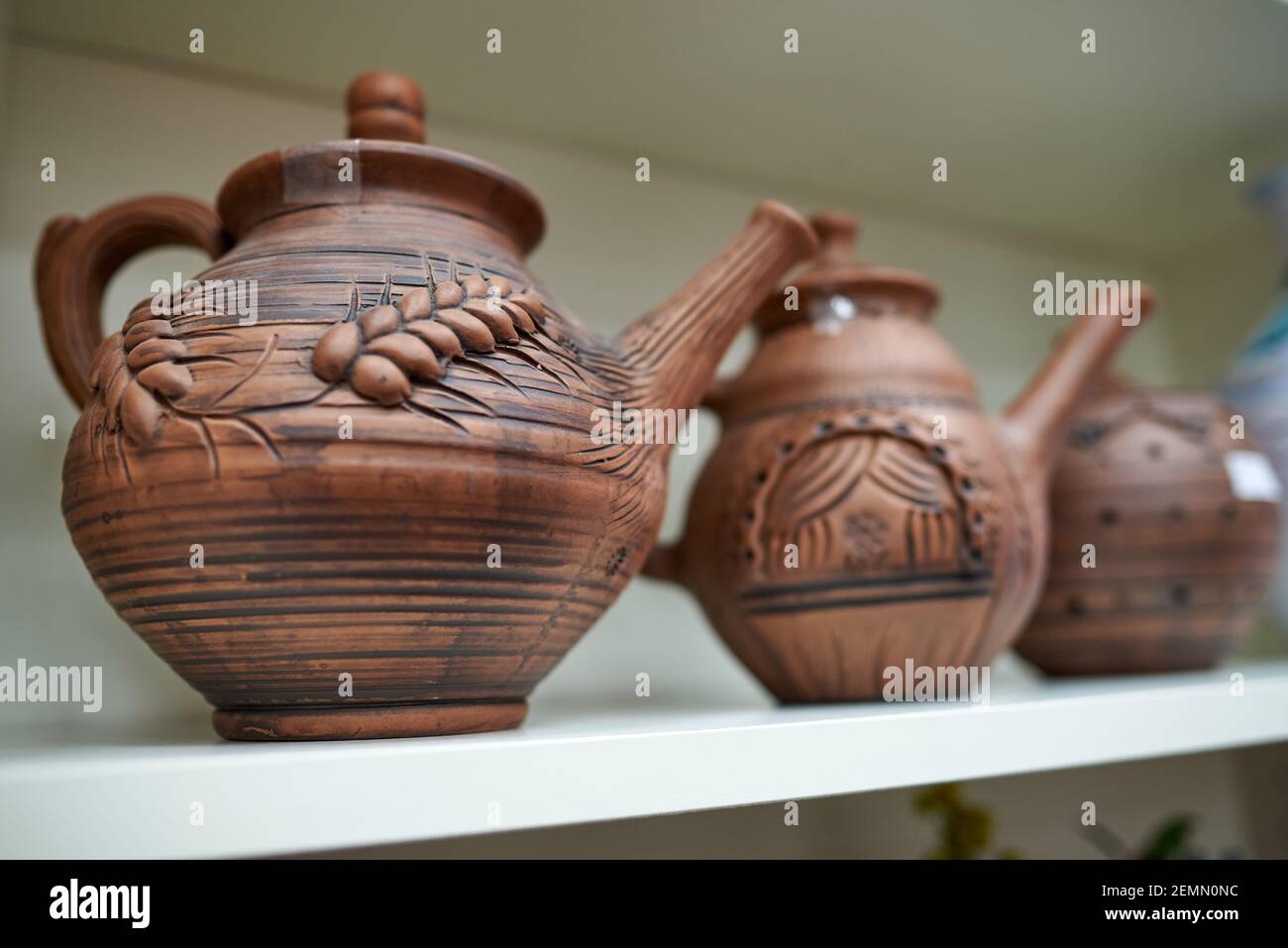 Clay teapots with an image of an ear, a flower on the window Stock