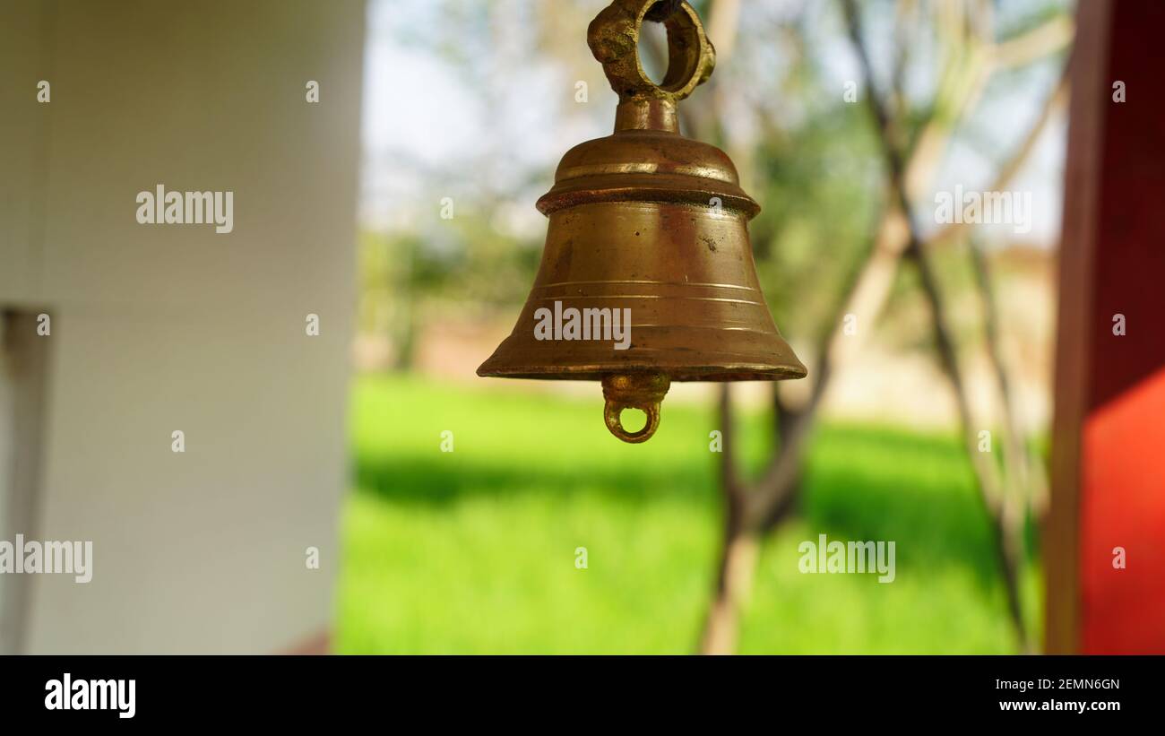 Bronze bell in indian temple in the green crops blur background. Hindu  temple brass bell hanging in gold color Stock Photo - Alamy
