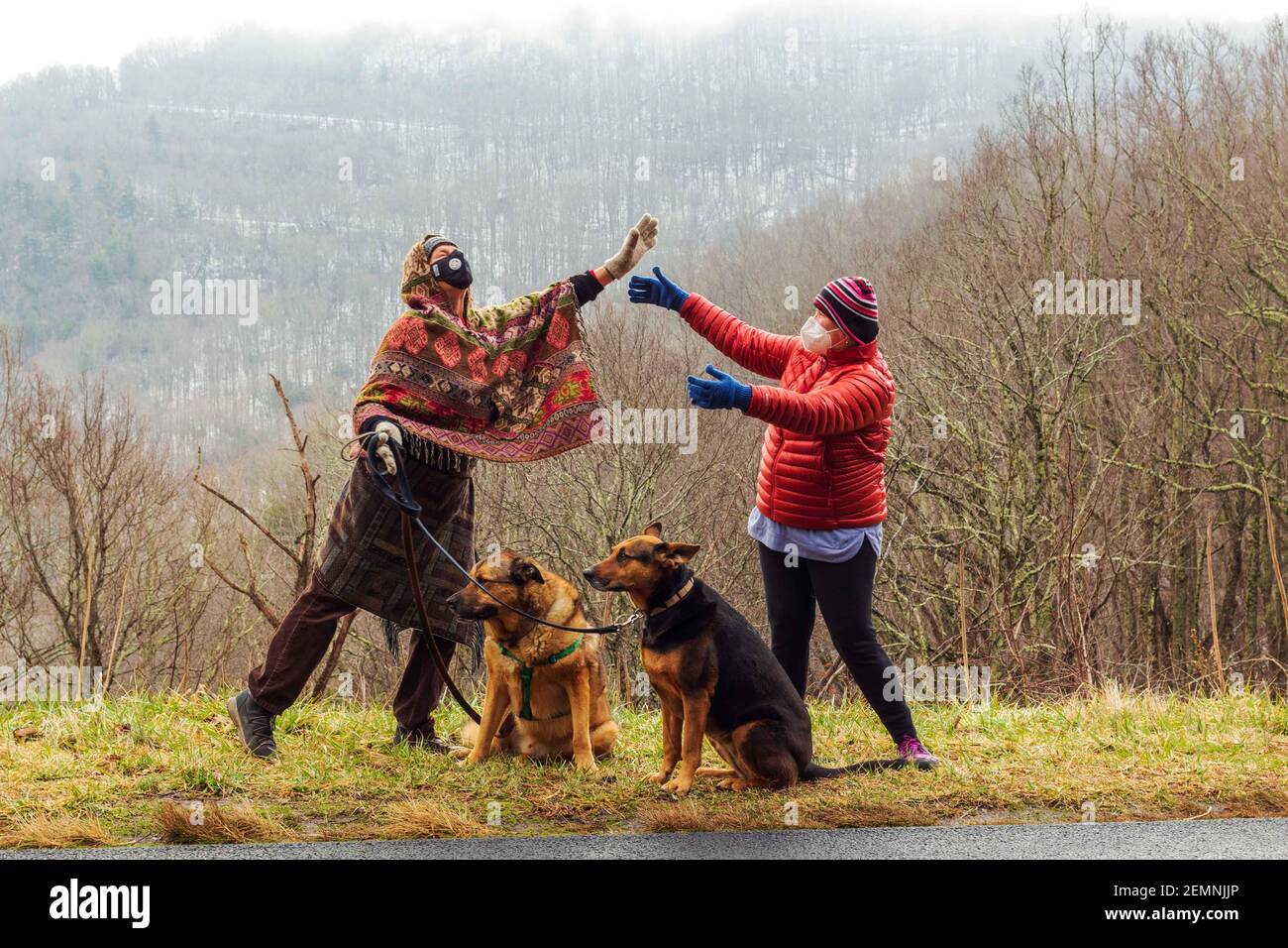 Two friends greet each other effusively, during the pandemic winter of social distancing, on the Blue Ridge Parkway in Asheville, NC, USA. Stock Photo