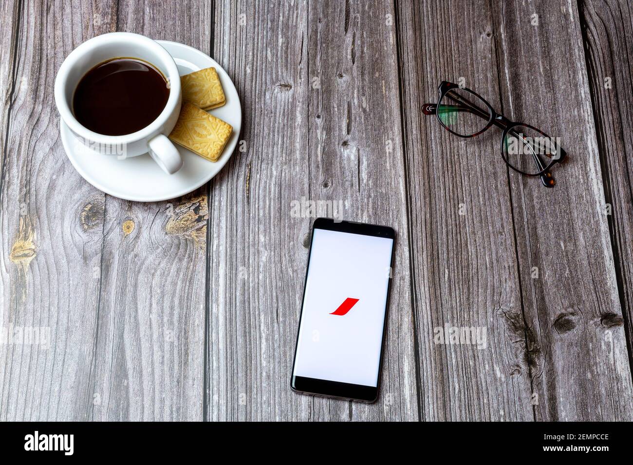 A mobile phone or cell phone on a wooden table with the Air France app open next to a coffee and glasses Stock Photo