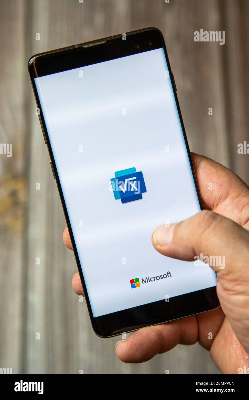 A mobile phone or cell phone being held by a hand with the microsoft