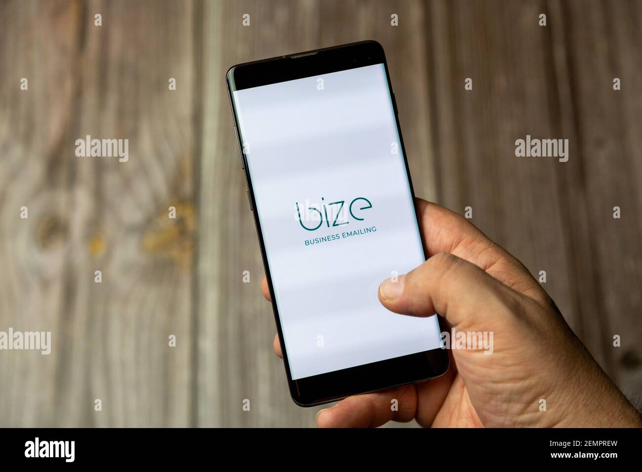 A mobile phone or cell phone being held by a hand with the Bize business emailing app open on screen Stock Photo