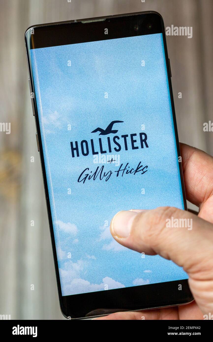 A mobile phone or cell phone being held by a hand with the Hollister app open on screen Stock Photo