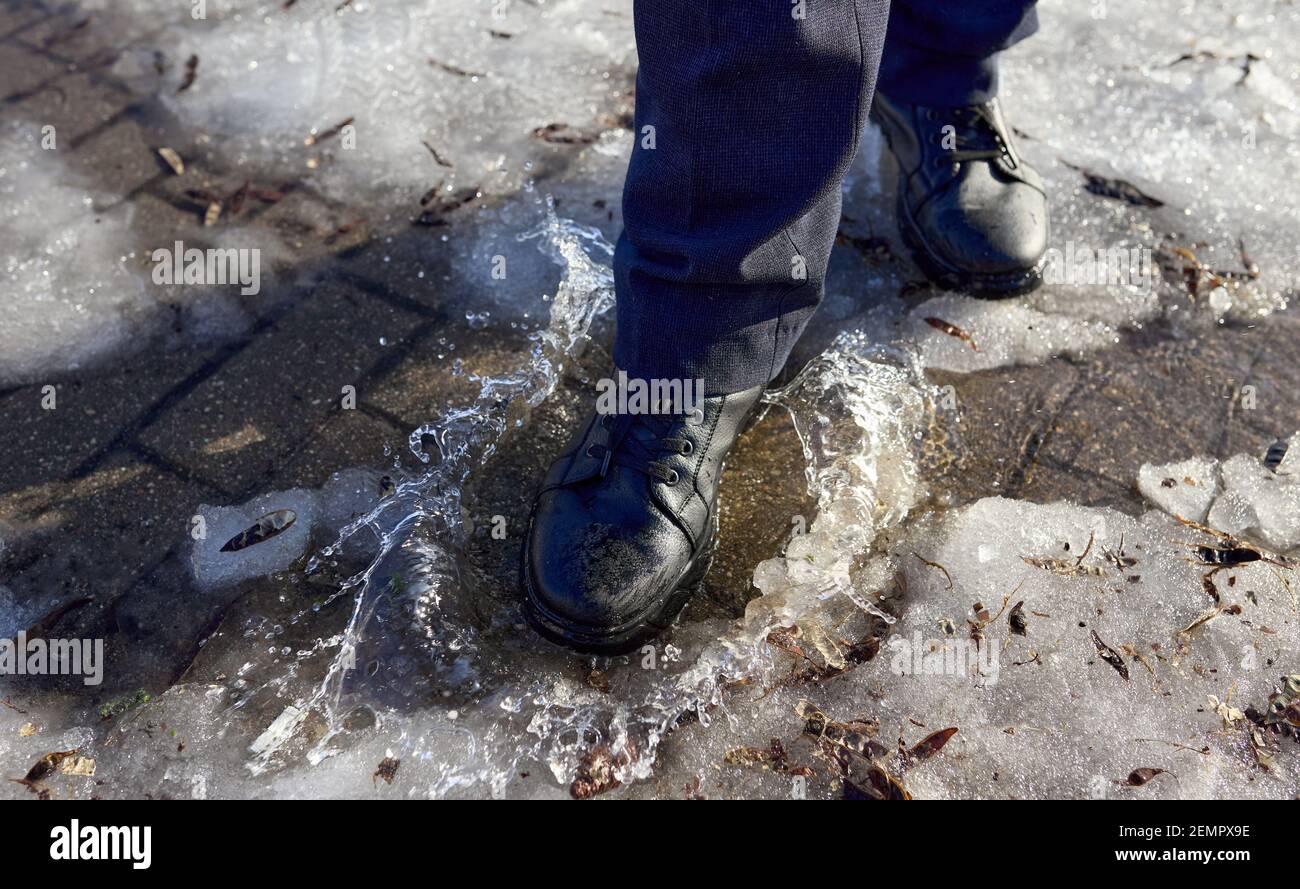 Male feet in shoes walk on a puddle of melted snow Stock Photo - Alamy