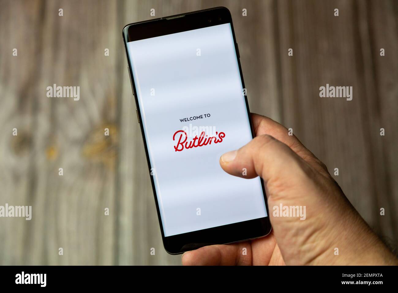 A mobile phone or cell phone being held by a hand with the Butlins holidays app open on screen Stock Photo