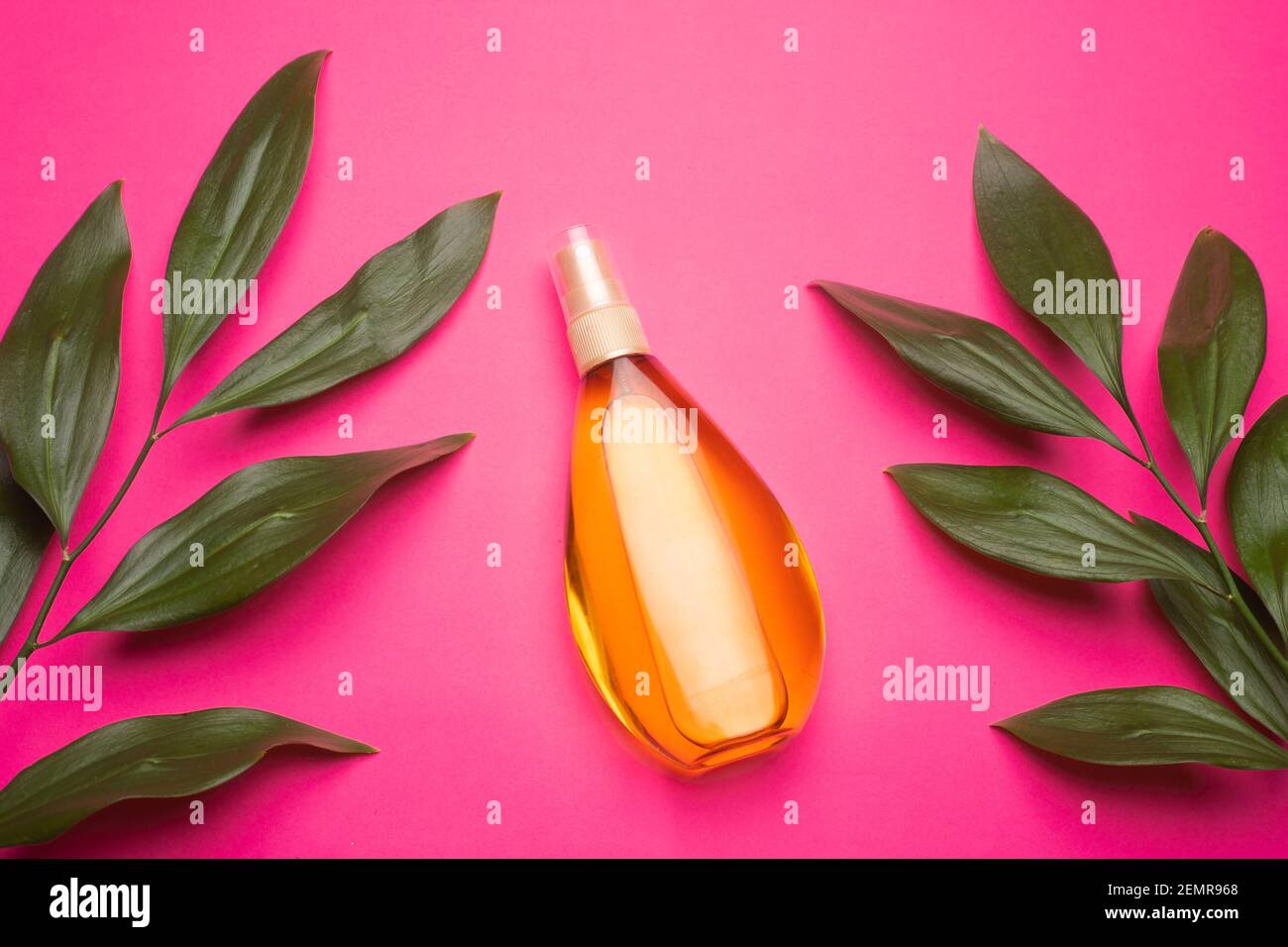 Suntan oil on a pink background . Suntan oil and green leaves. Vacation. Protect your skin from the sun. Uniform tan. Article about vacation. Article Stock Photo