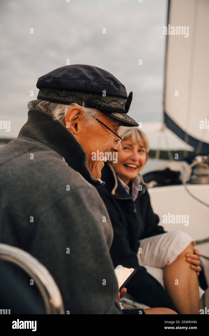 Cheerful senior couple laughing while talking with each other on boat during sunset Stock Photo