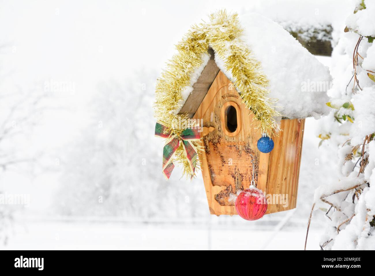 Birdhouse decorated with Christmas ornaments in heavy snowfall; with copy space Stock Photo
