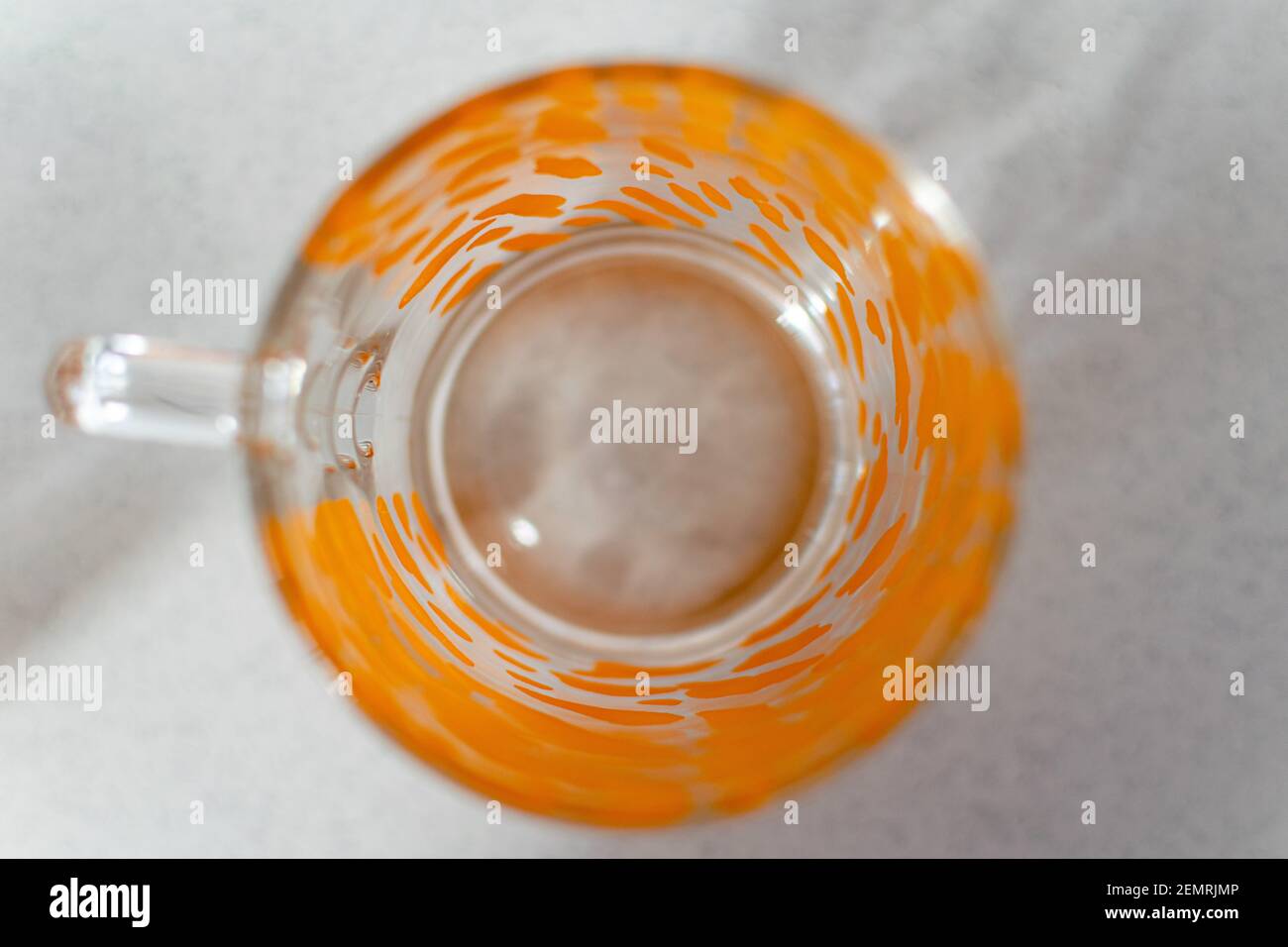 a single glass cup with a orange pattern on a white background from above Stock Photo