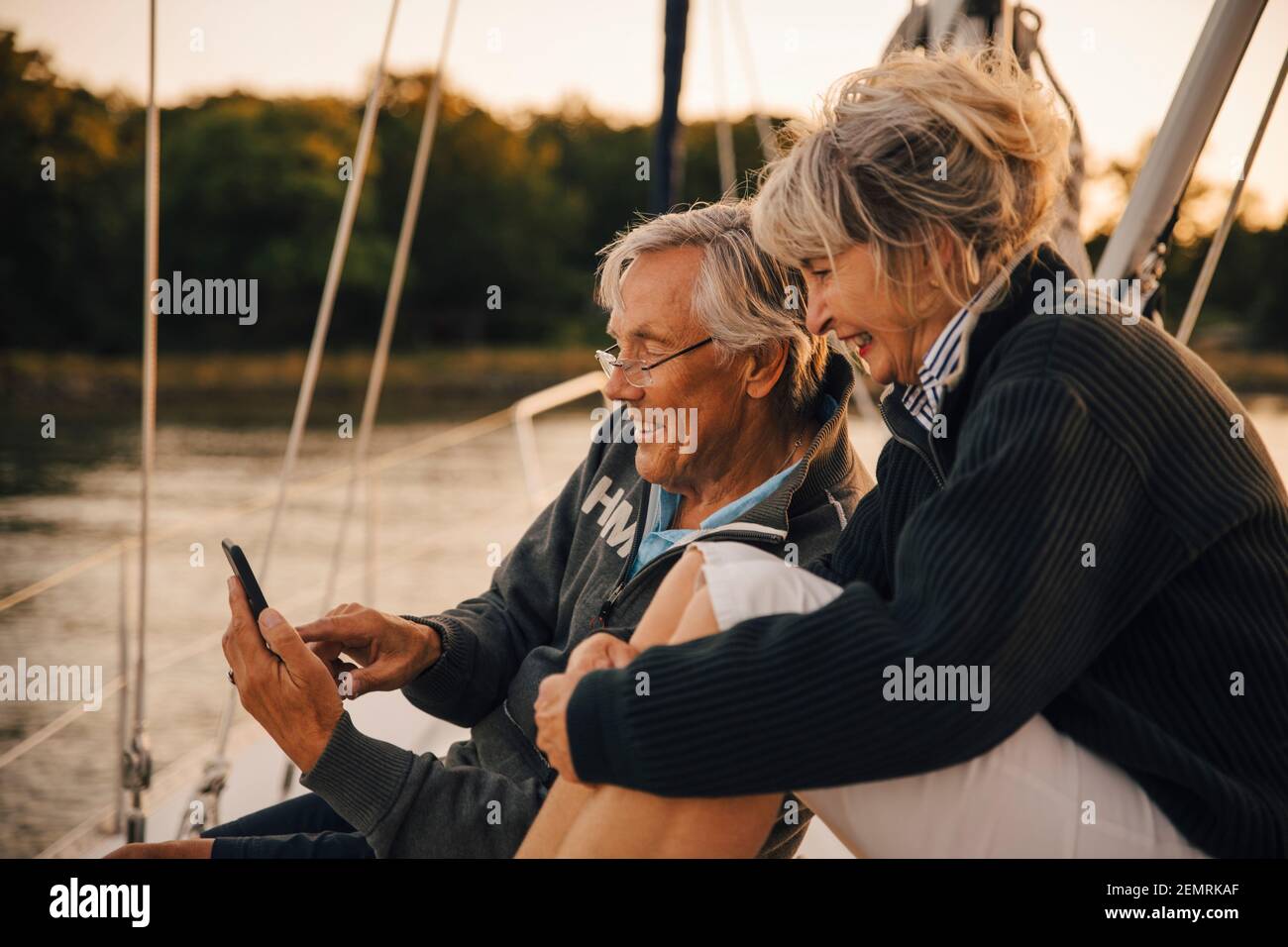 Smiling heterosexual couple using smart phone during sunset Stock Photo