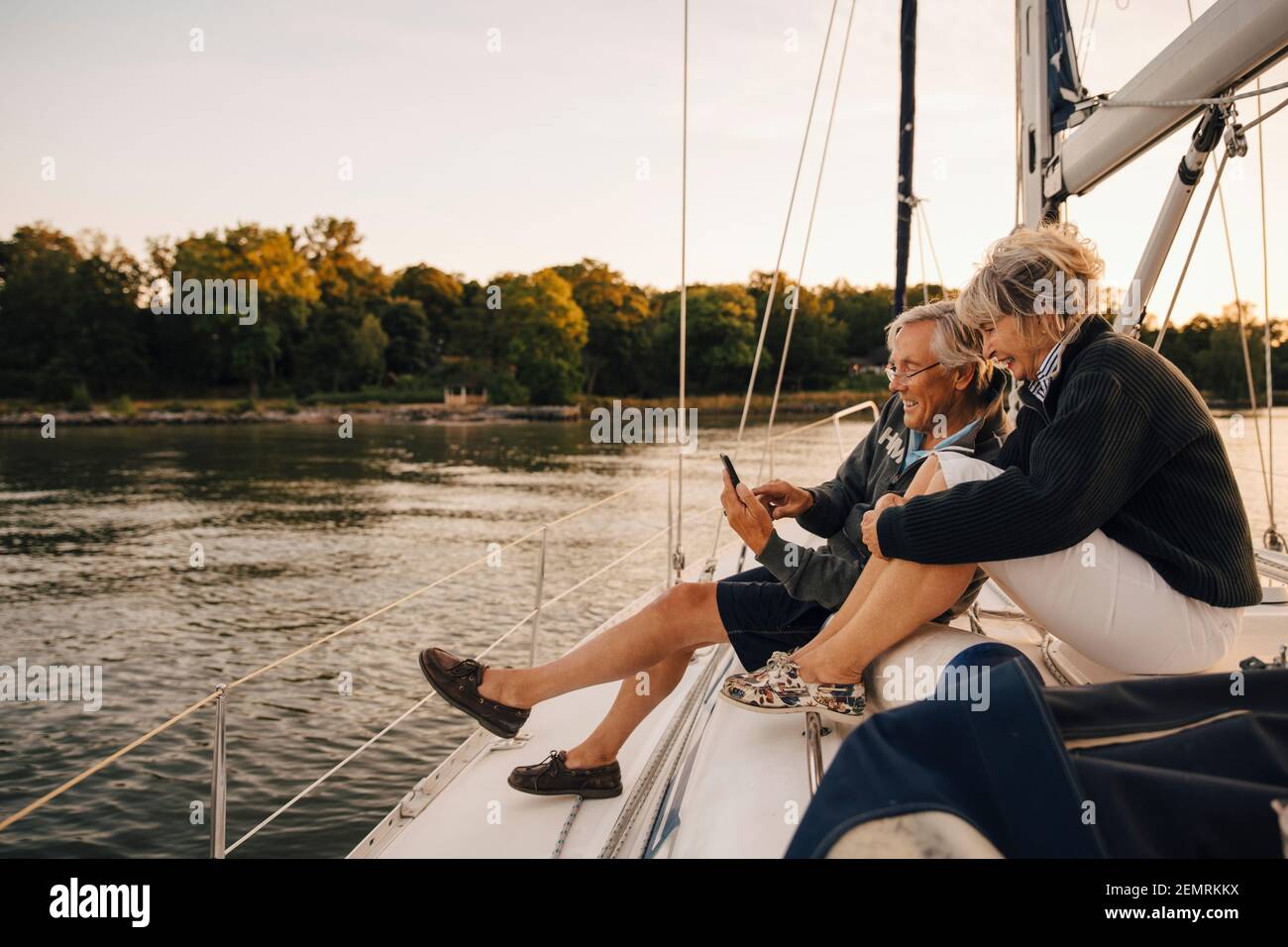 Happy senior couple using mobile phone during sunset Stock Photo