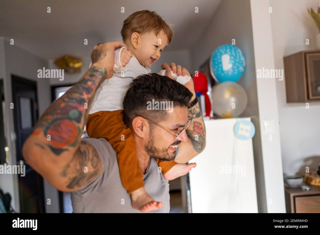 Happy father carrying son on shoulder while standing at home Stock Photo