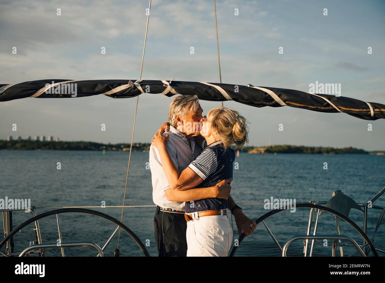 Senior couple lip kissing in boat against sea and sky on sunny day Stock Photo
