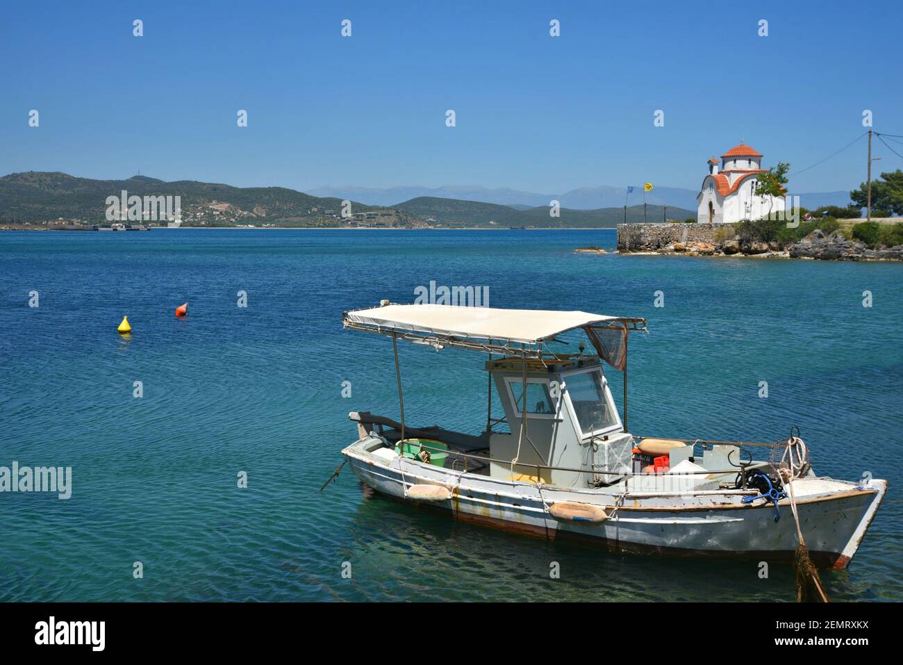 Seascape with a picturesque Greek fishing boat and view of the Byzantine chapel of Saint Peter and Paul in Gytheio, Laconia Greece. Stock Photo