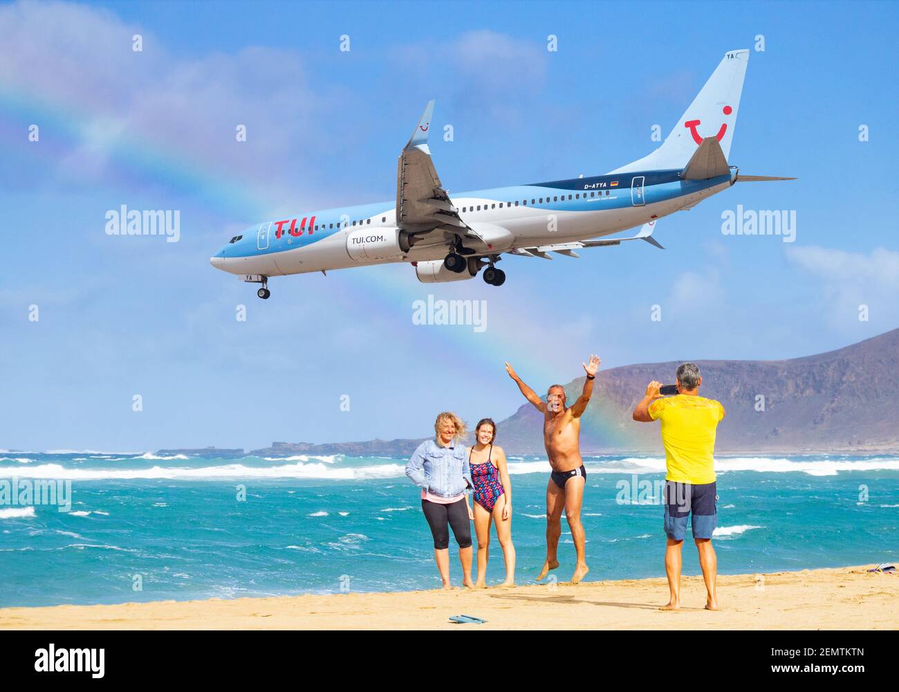 Composite image of TUI aircraft flying over beach in Spain with rainbow in sky. Stock Photo