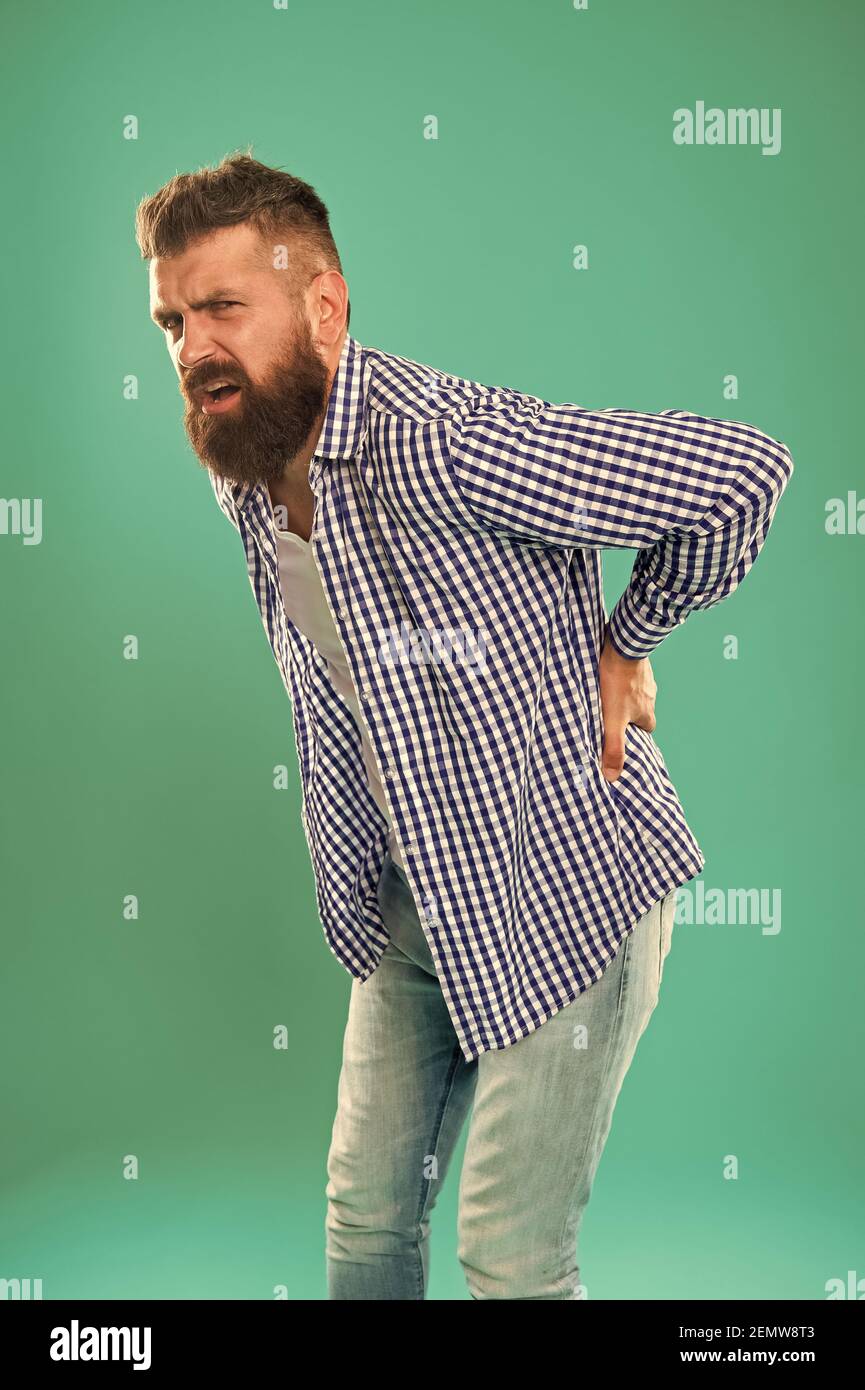 Bent over feeling sharp pain in back. Bearded man suffer from pain